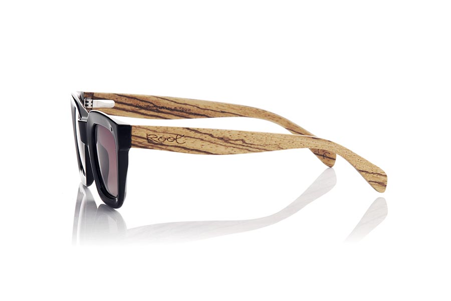 Gafas de Madera Natural de Walnut OONA. Las gafas de sol OONA son el accesorio perfecto para completar tu look. Con una montura frontal en color negro satinado de forma cuadrada y esquinas redondeadas, estas gafas tienen un toque moderno y sofisticado. Las varillas anchas son de madera de zebrano, creando un hermoso contraste de color. Estas gafas son ideales para mujeres que buscan algo diferente y único. Además, montan lentes marrón gradient que ofrecen protección contra los rayos UV. Siéntete elegante y protegida del sol con las gafas de sol OONA. Venta al Por Mayor y Detalle | Root Sunglasses® 